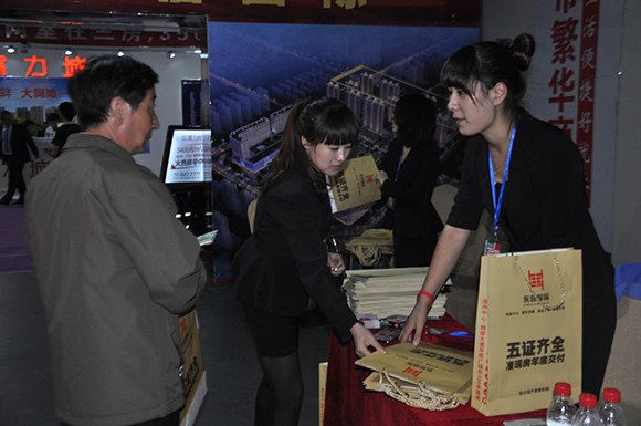 購(gòu)房者認(rèn)真聽置業(yè)顧問(wèn)講解